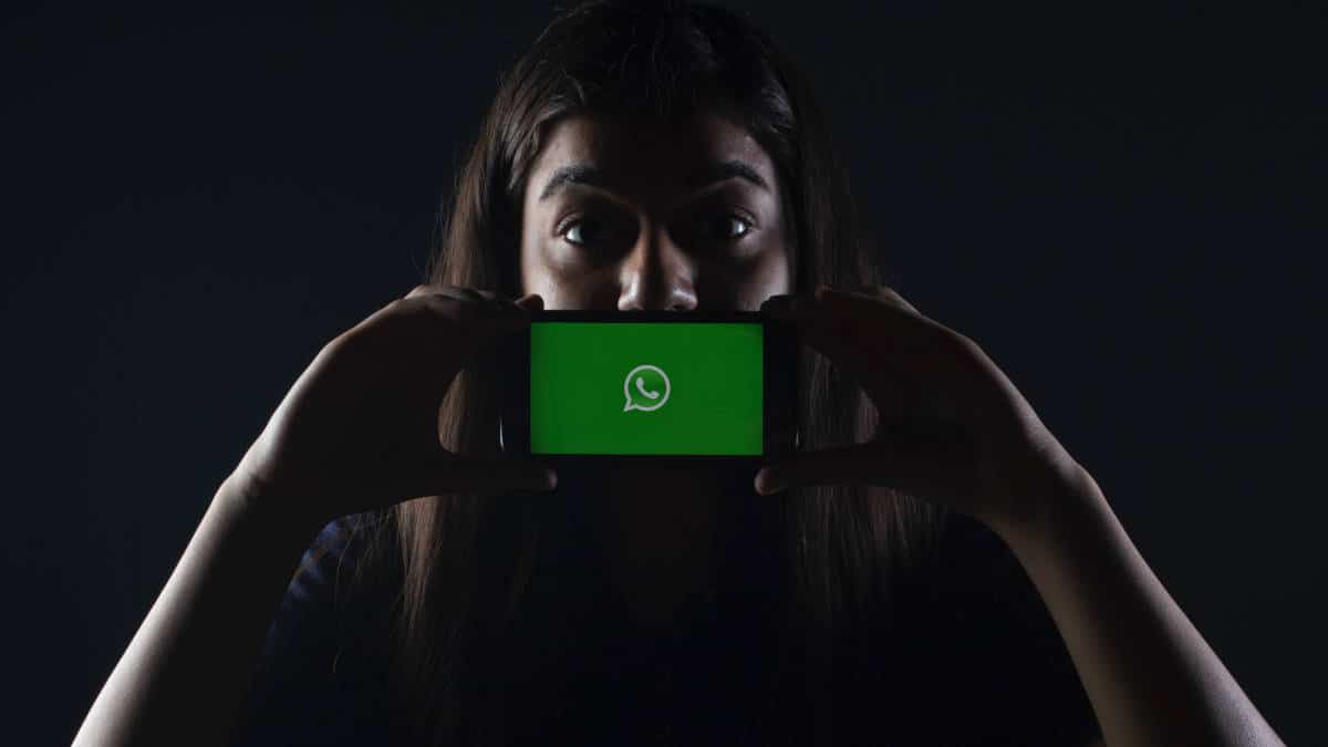 ragazza che esprime stupore con cellulare e schermata WhatsApp